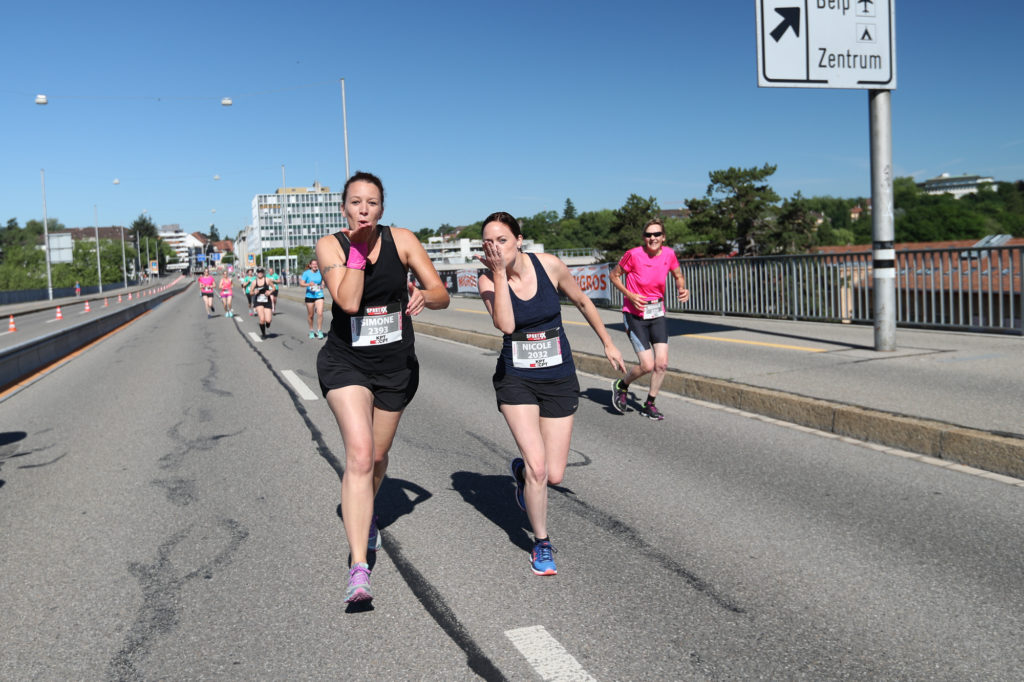 2 Läuferinnen machen Handküsse beim Überqueren der Monbijou-Brücke beim Frauenlauf in Bern