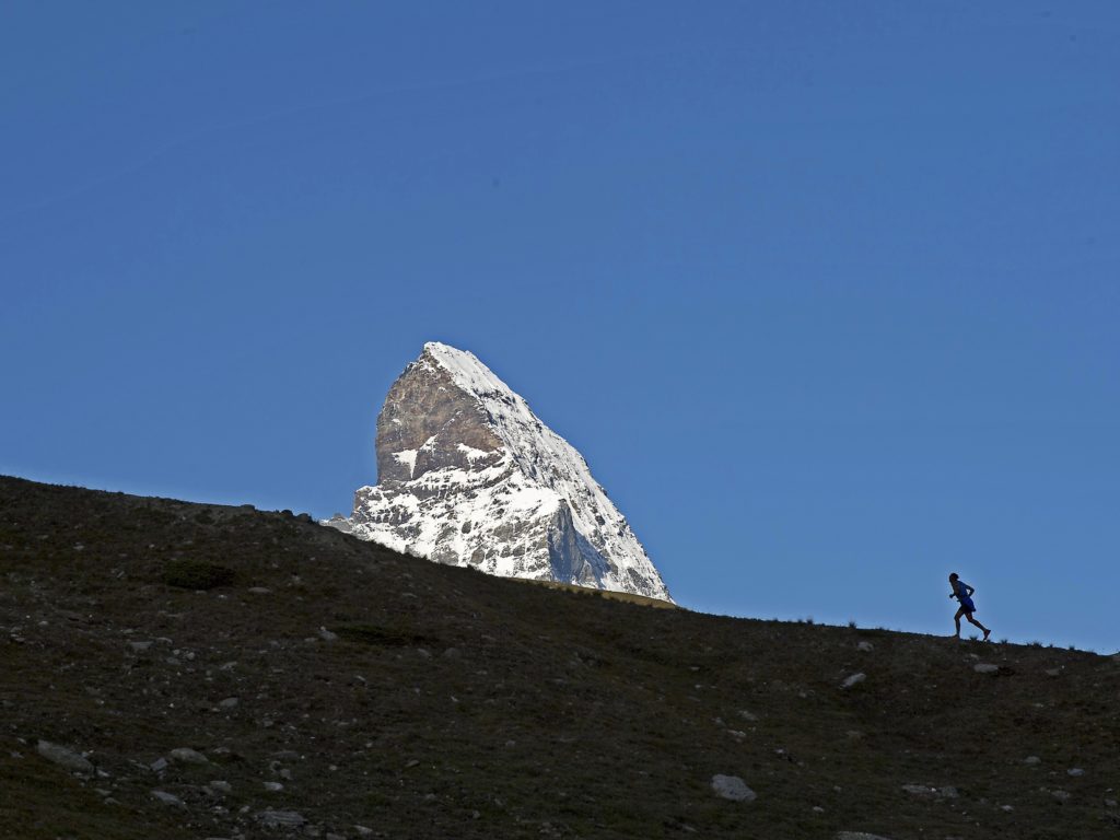 Läufer vor tollem Panorama, im Hintergrund in der Sonne das Matterhorn